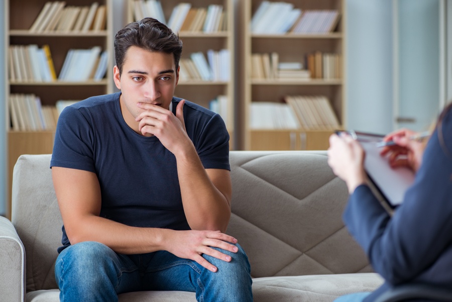 man sitting while listening to his therapist