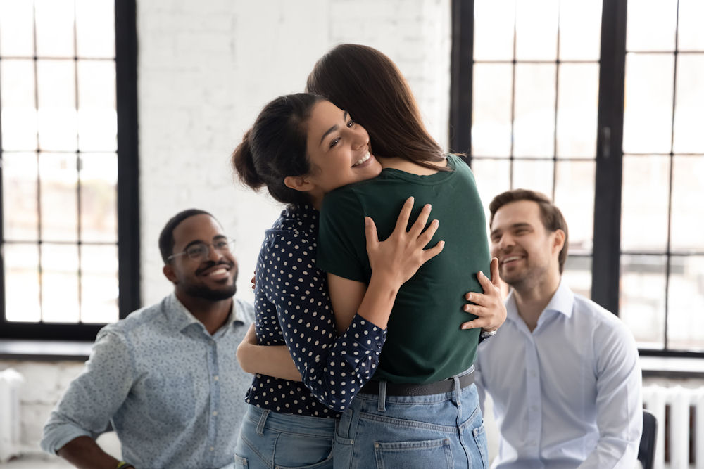 women-hugging-each-other-in-group-therapy