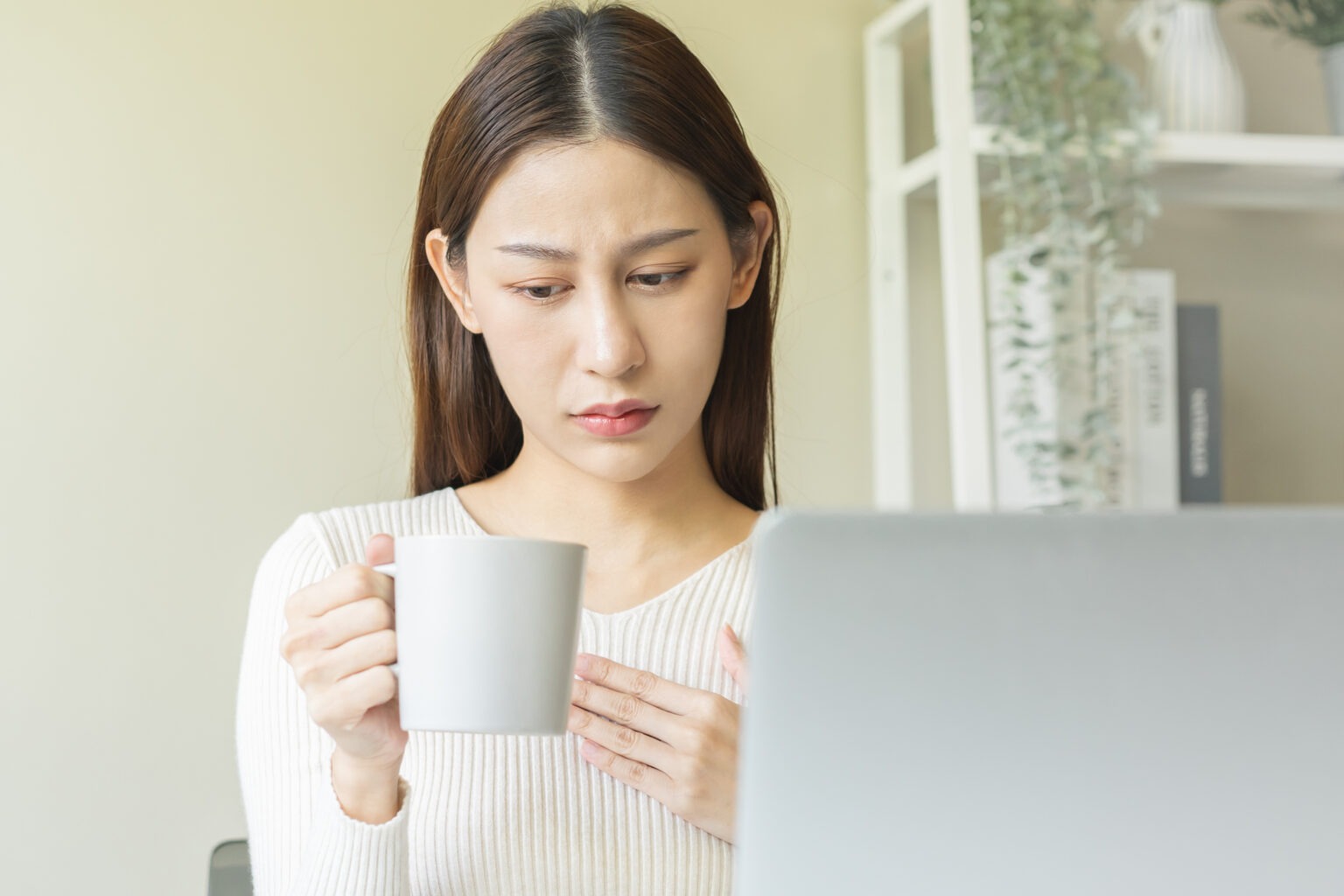 a woman holding a cup of coffee while holding her chest