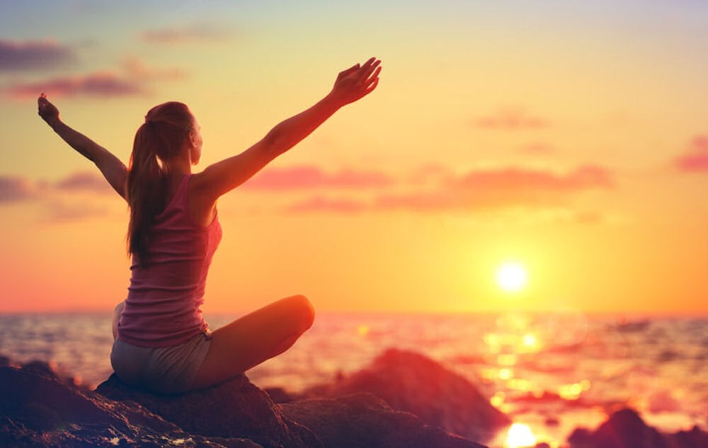 woman-on-a-rock-arms-outstretched-watching-the-sunrise