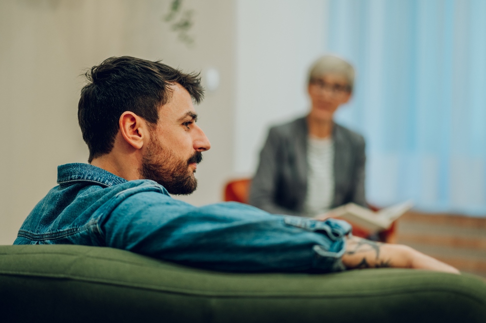 a young man sitting on a green couch in therapy